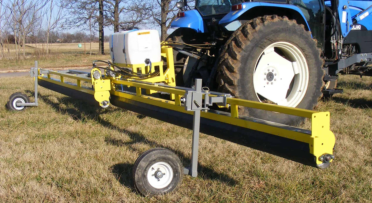 GrassWorks 3 Point Tractor Mount Weed Wiper™ with gauge wheels, attached to a blue tractor in a pasture.