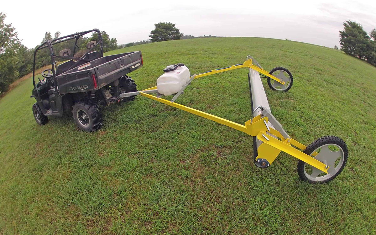 A pull-type GrassWorks Weed Wiper attached to a utility vehicle, designed for large-area weed management.