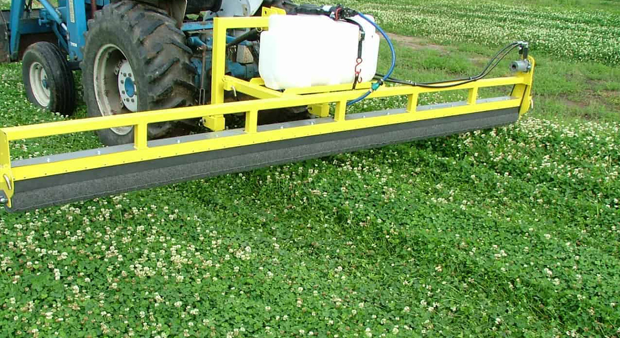 GrassWorks Weed Wiper™ applying herbicide over a dense clover field to control invasive weeds.