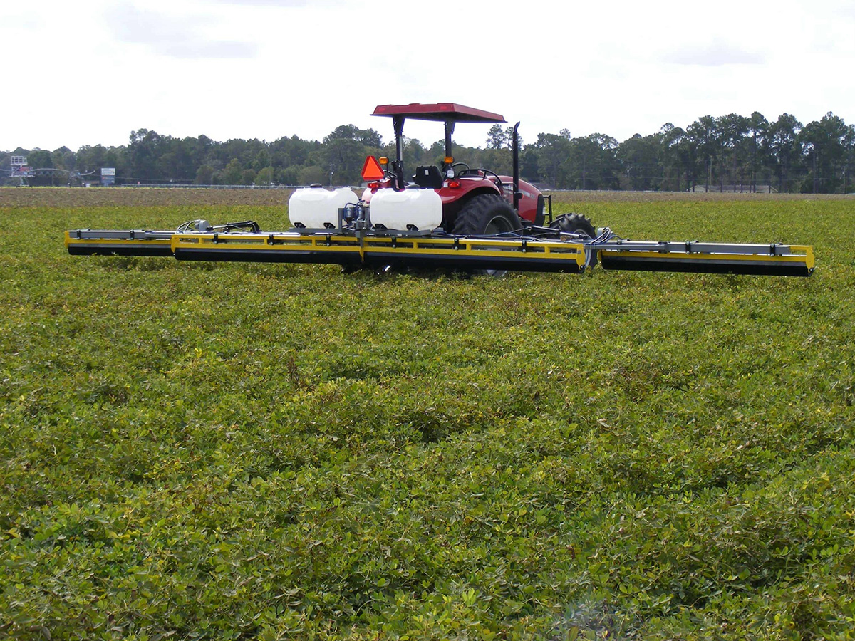 A GrassWorks Weed Wiper with extended arms applying herbicide across a large field, ensuring precise weed control while protecting desirable crops.